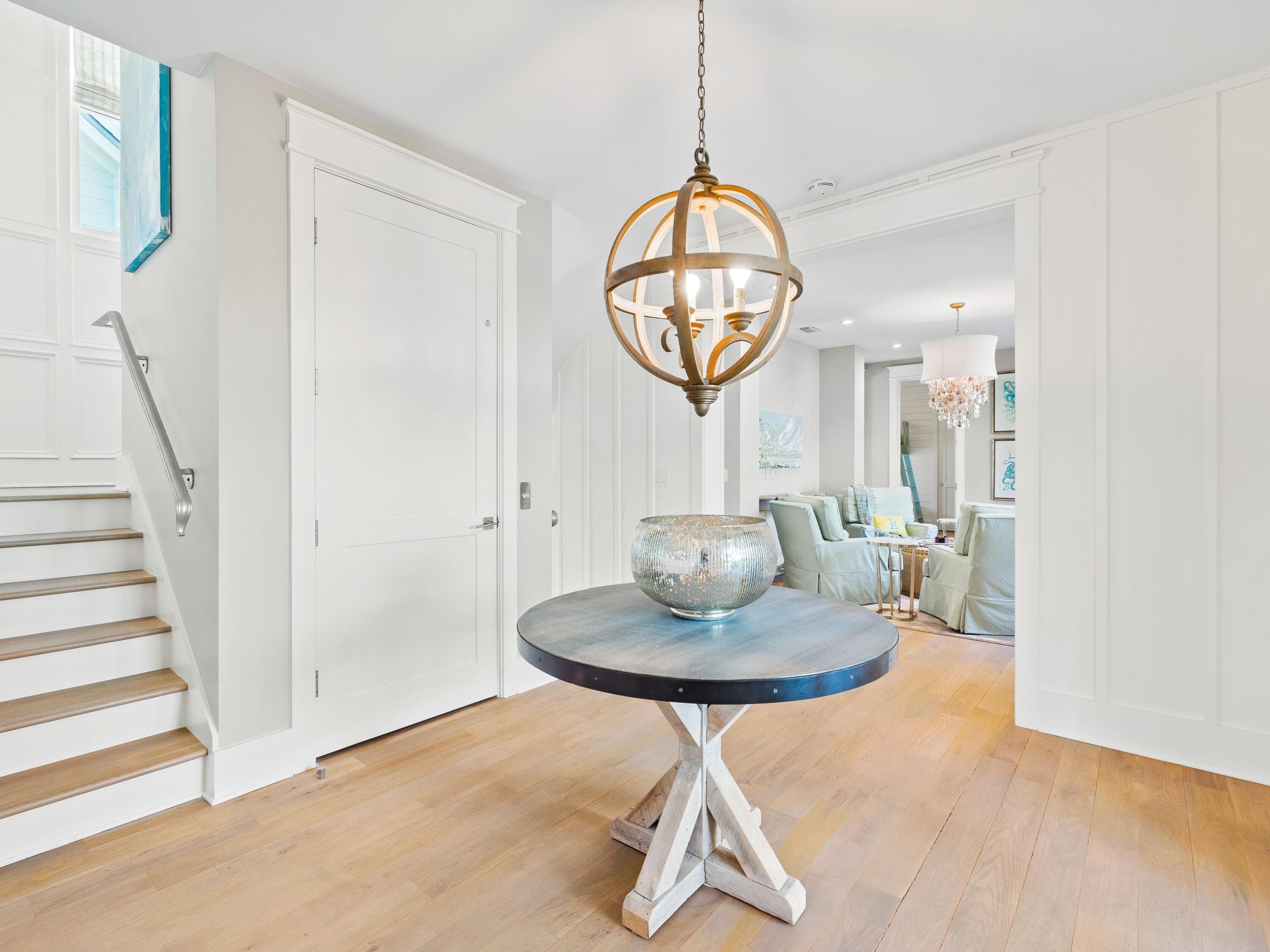 An entry hallway lit by a wood and iron orb chandelier